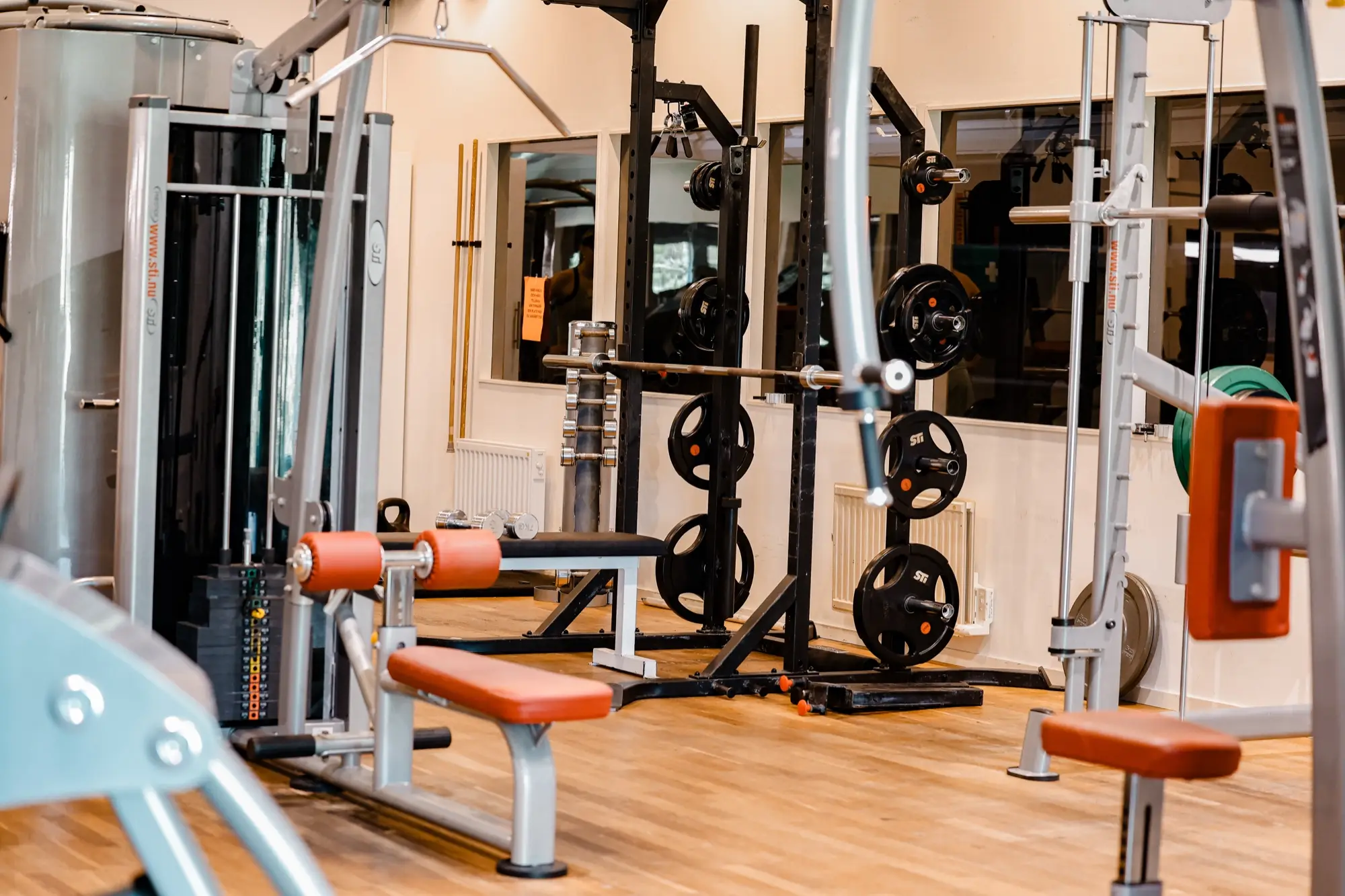 Gymmet med skivstångsställning, bänkar och speglar längs väggen